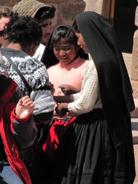 las mujeres de la isla taquile con su tipico velo negro. vendiendo artesanias a los turistas que llegan al lugar.